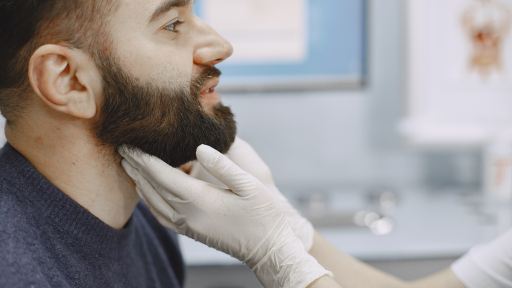 Ein Arzt untersucht den Halsbereich eines Patienten